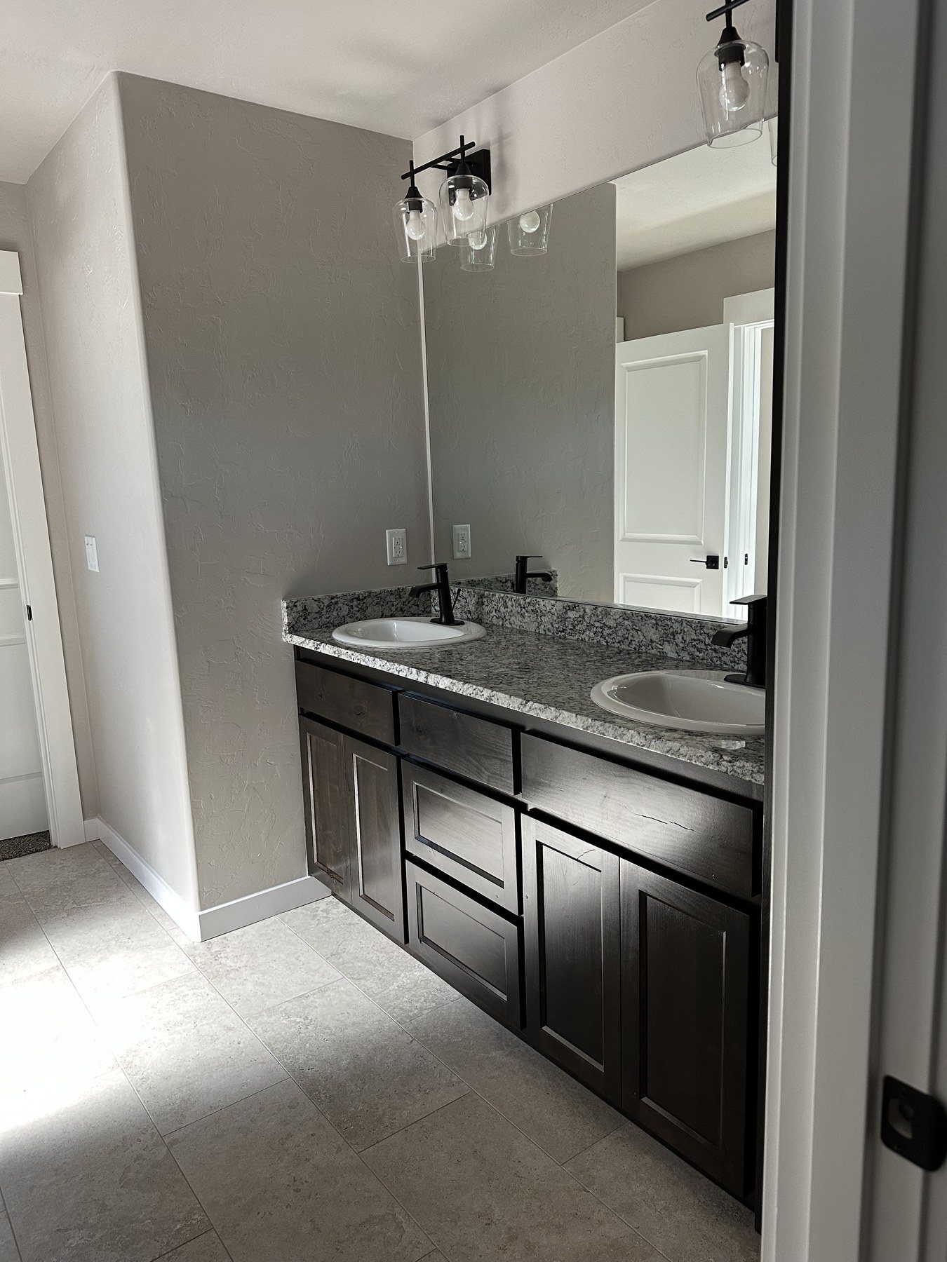 Bathroom double vanity with granite counters, framed mirrors and matte black fixtures
